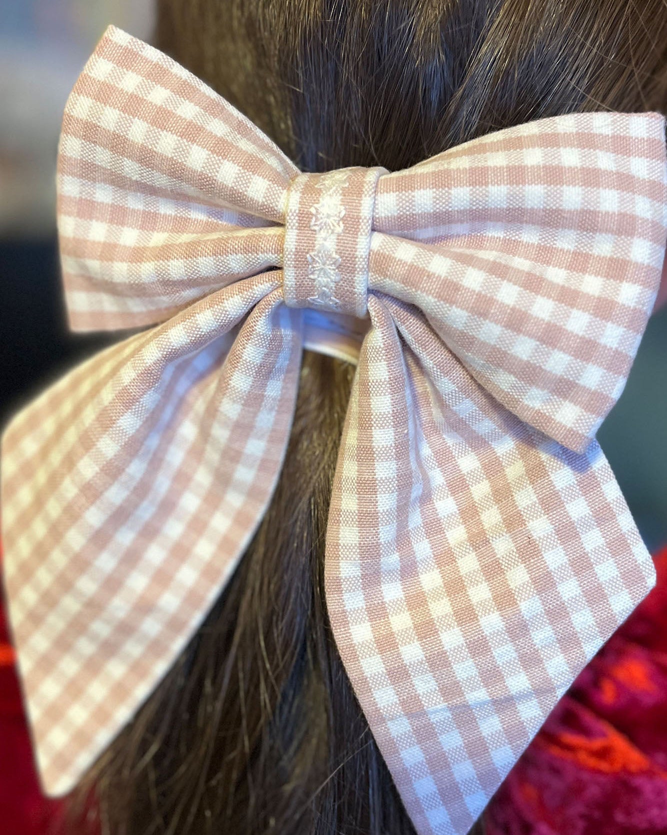 Checkered bow hair accessory on a person's head with a blurred background