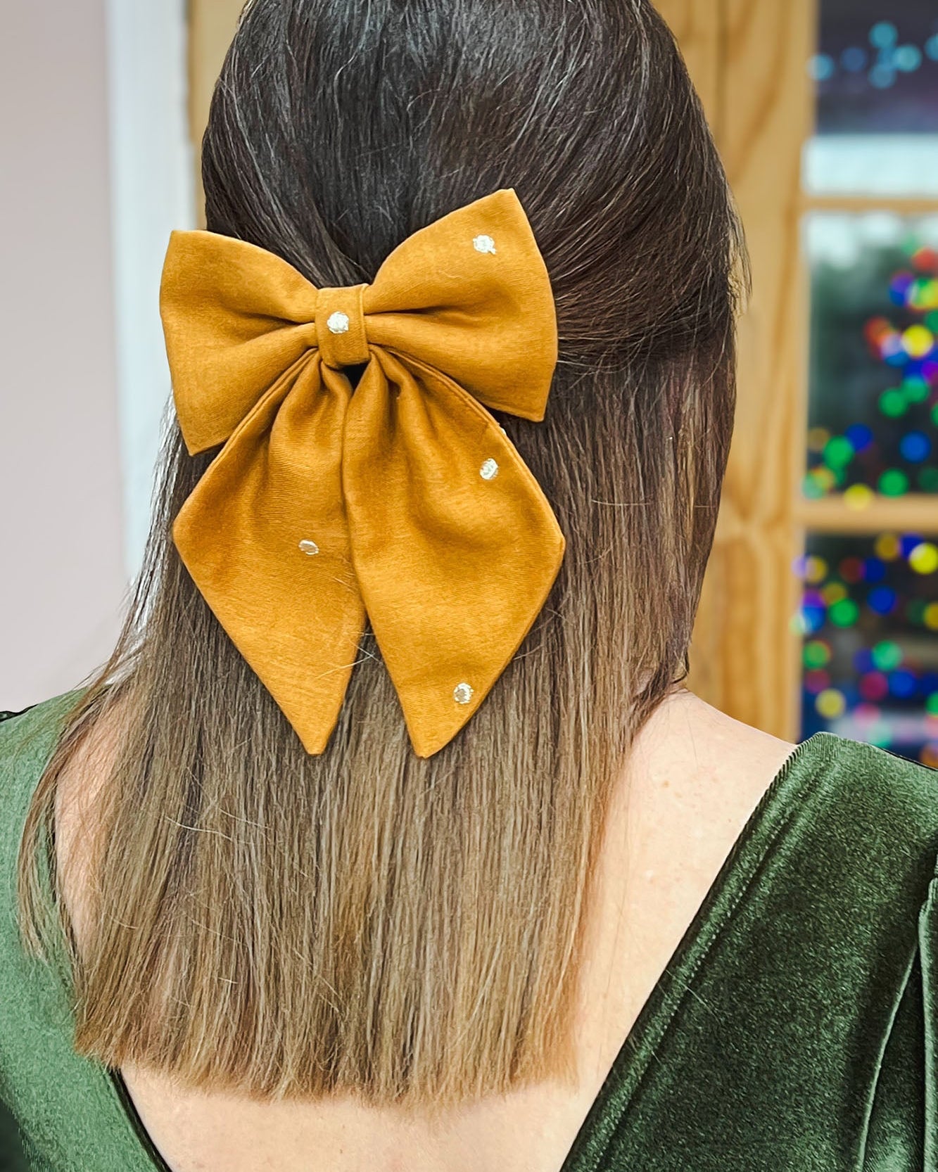 Person with a mustard yellow hair bow in their hair, wearing a green top.