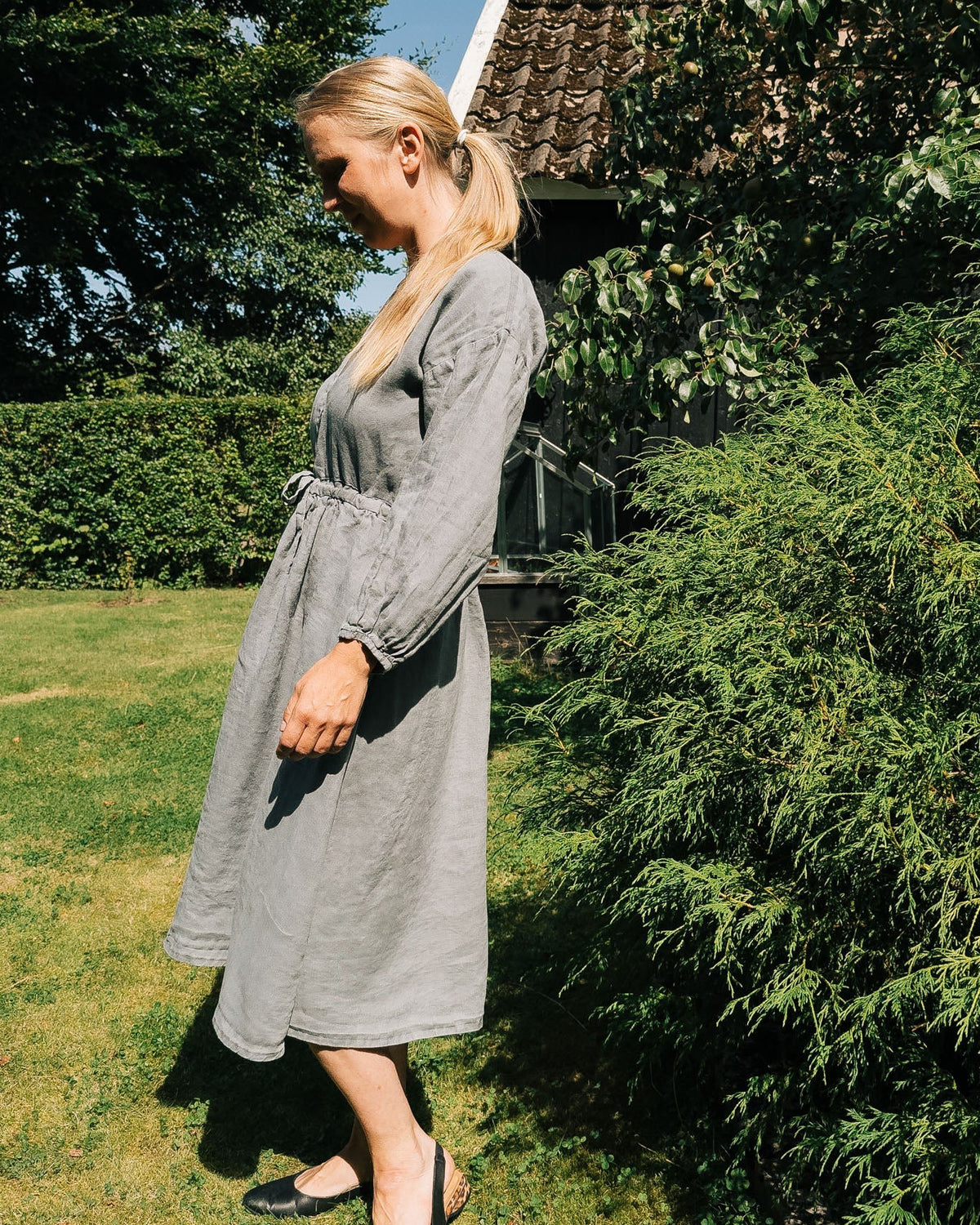 Woman in a gray dress standing in a garden