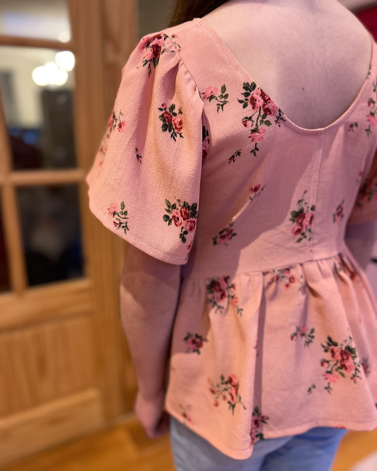 Pink floral blouse worn by a person, with a blurred background