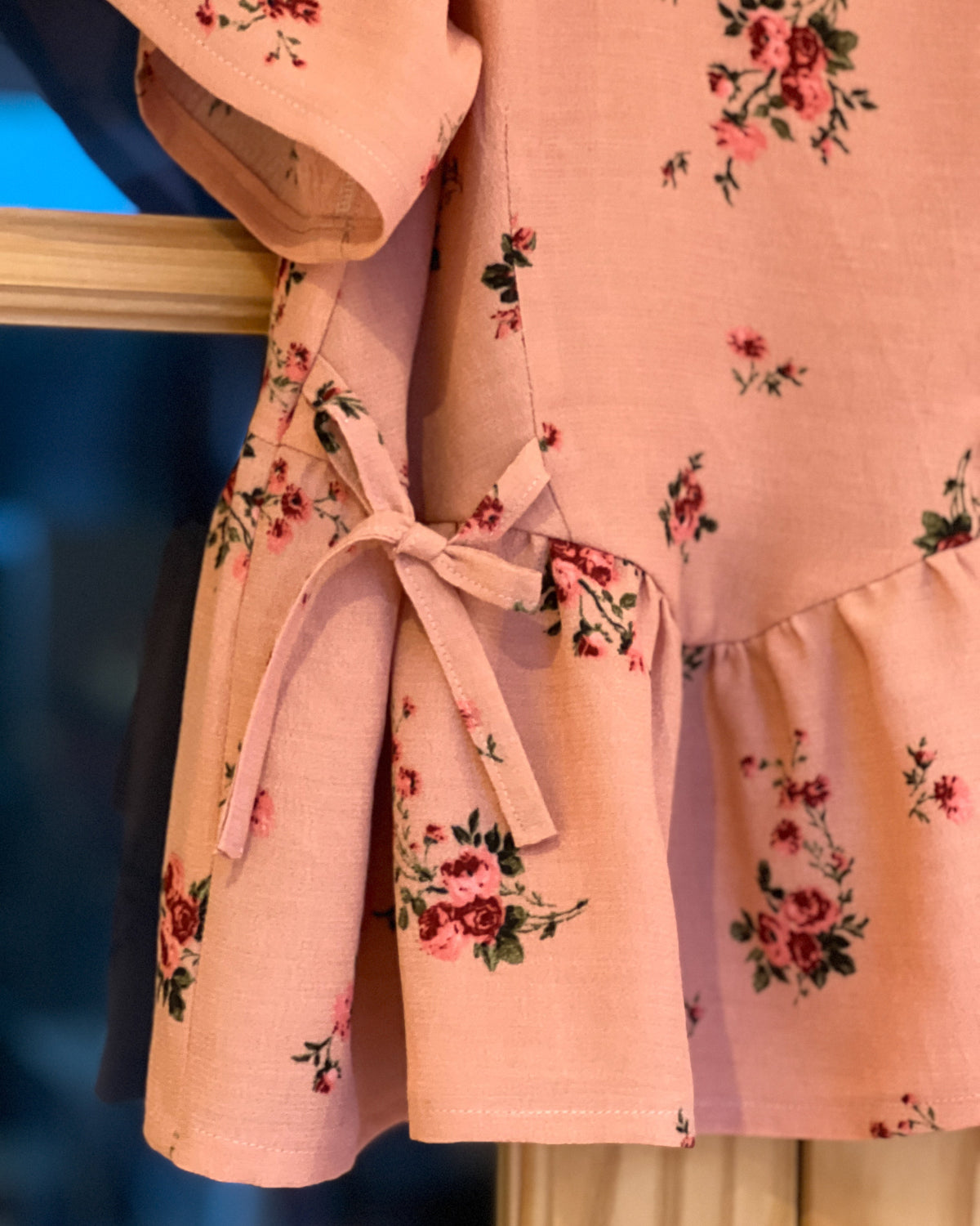 Pink floral dress with a bow detail on a blue background