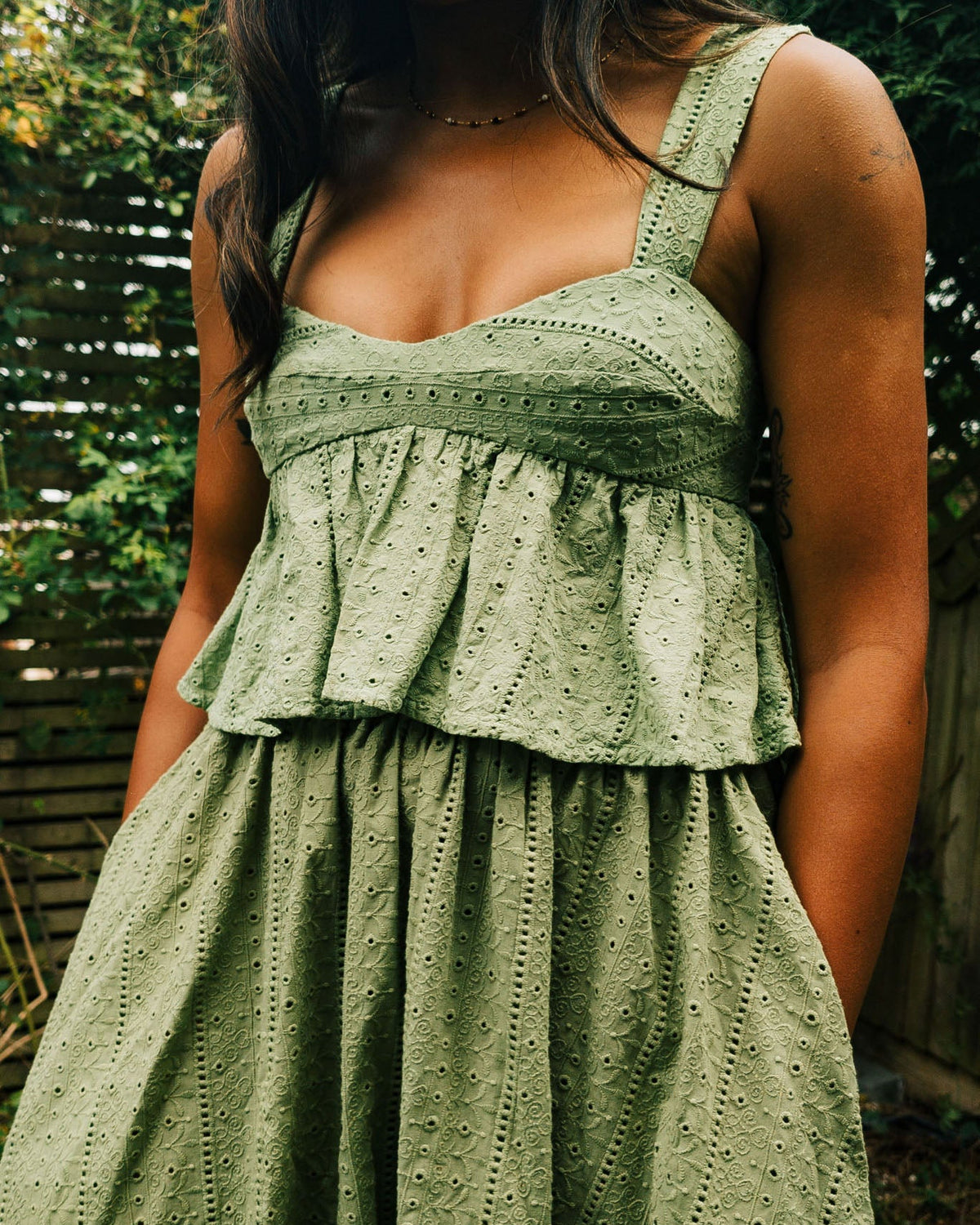 Woman wearing a green dress with a textured pattern outdoors.