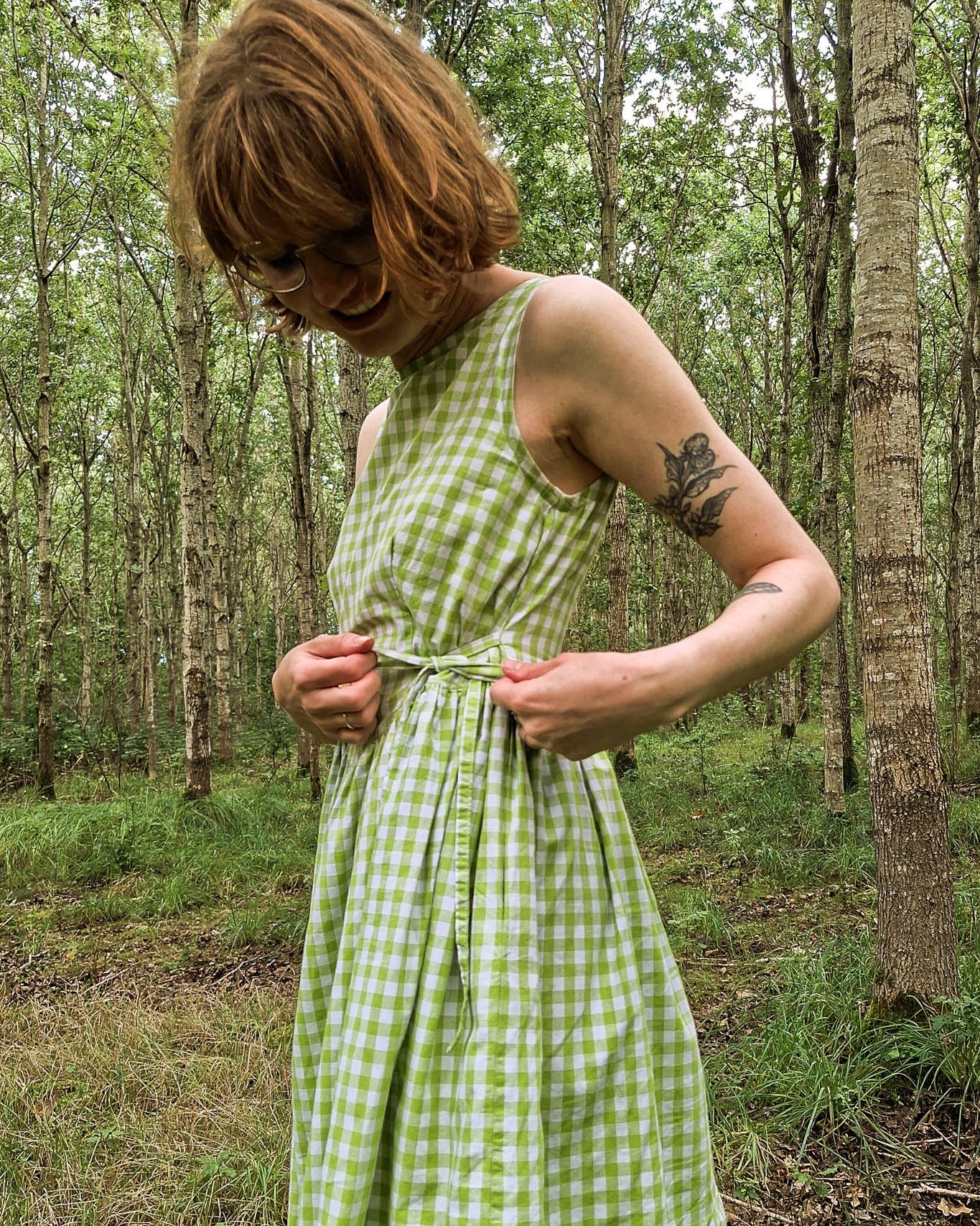 Person wearing a green checkered dress in a forest setting