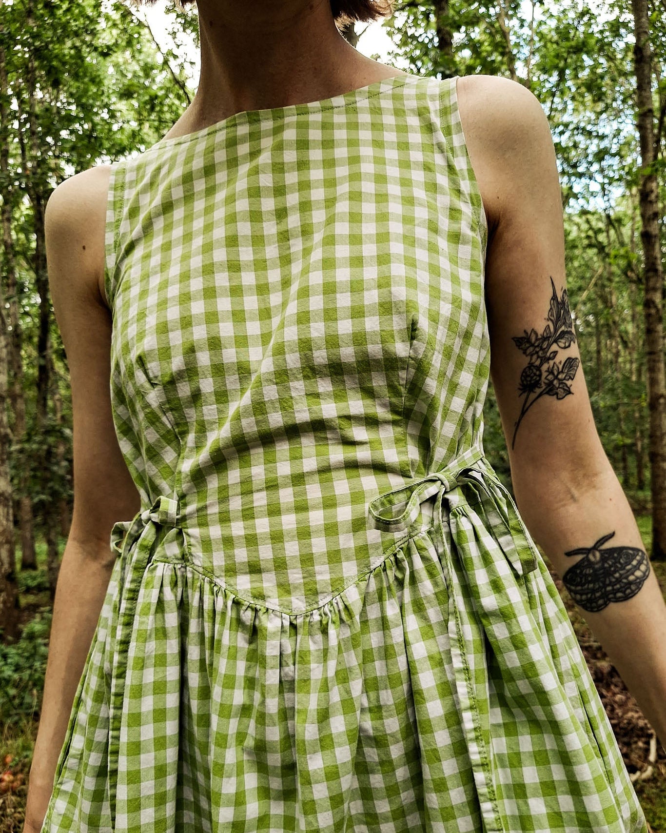 Person wearing a green checkered dress in a forest setting