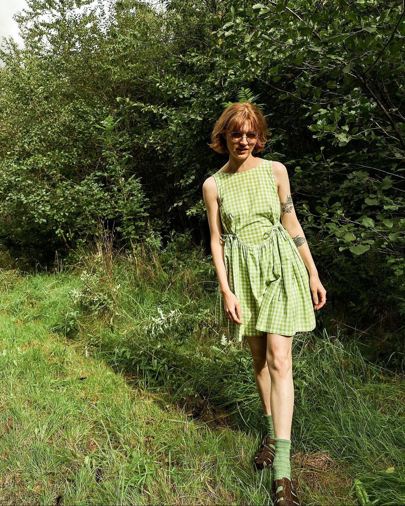 Woman in a green checkered dress standing in a forest