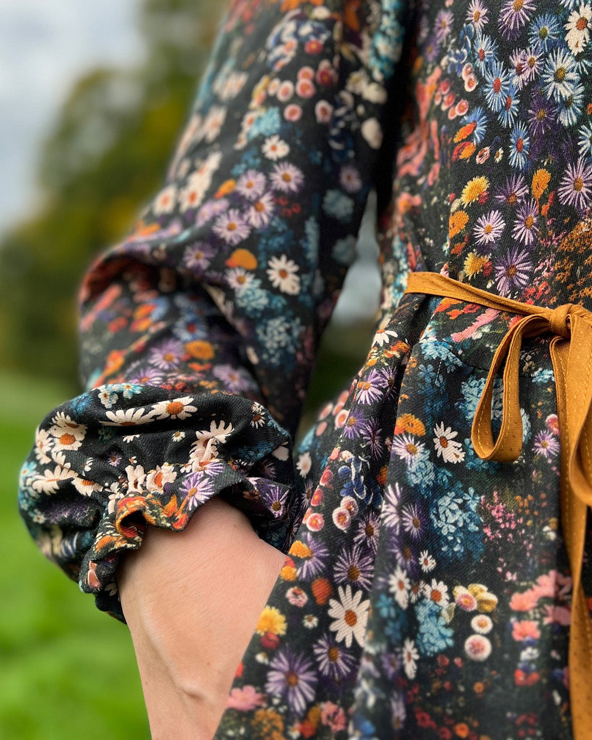 Close-up of a person wearing a floral dress with a blurred natural background