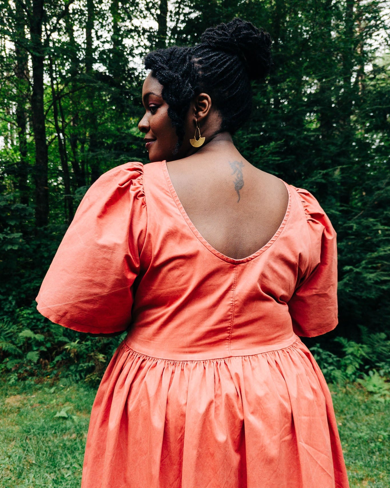 Woman in a coral dress standing in a forest