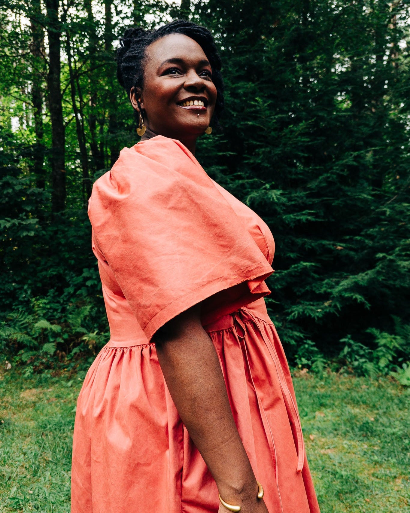 Woman in a coral dress standing in a forest
