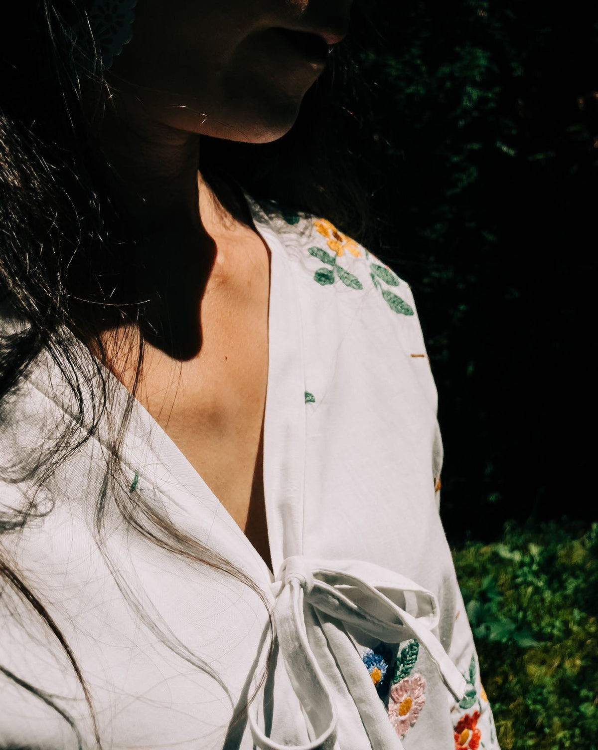 Woman wearing a white floral blouse against a dark background