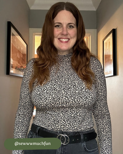 Woman wearing a leopard print top in a room with framed pictures on the wall.