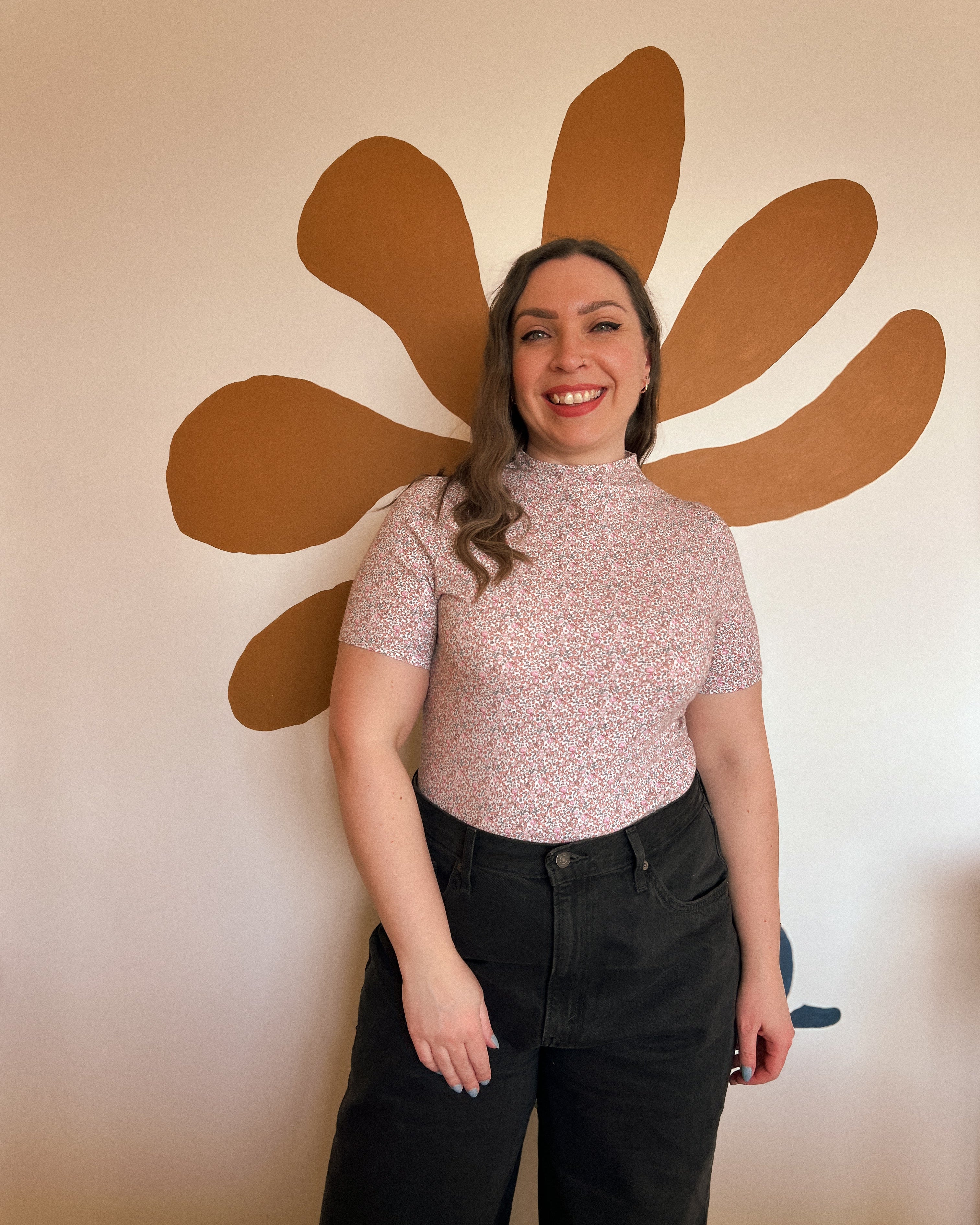 Woman standing in front of a large brown flower wall decoration