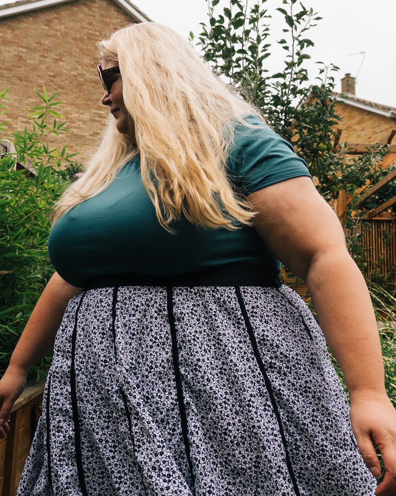 Woman wearing a green top and patterned skirt outdoors